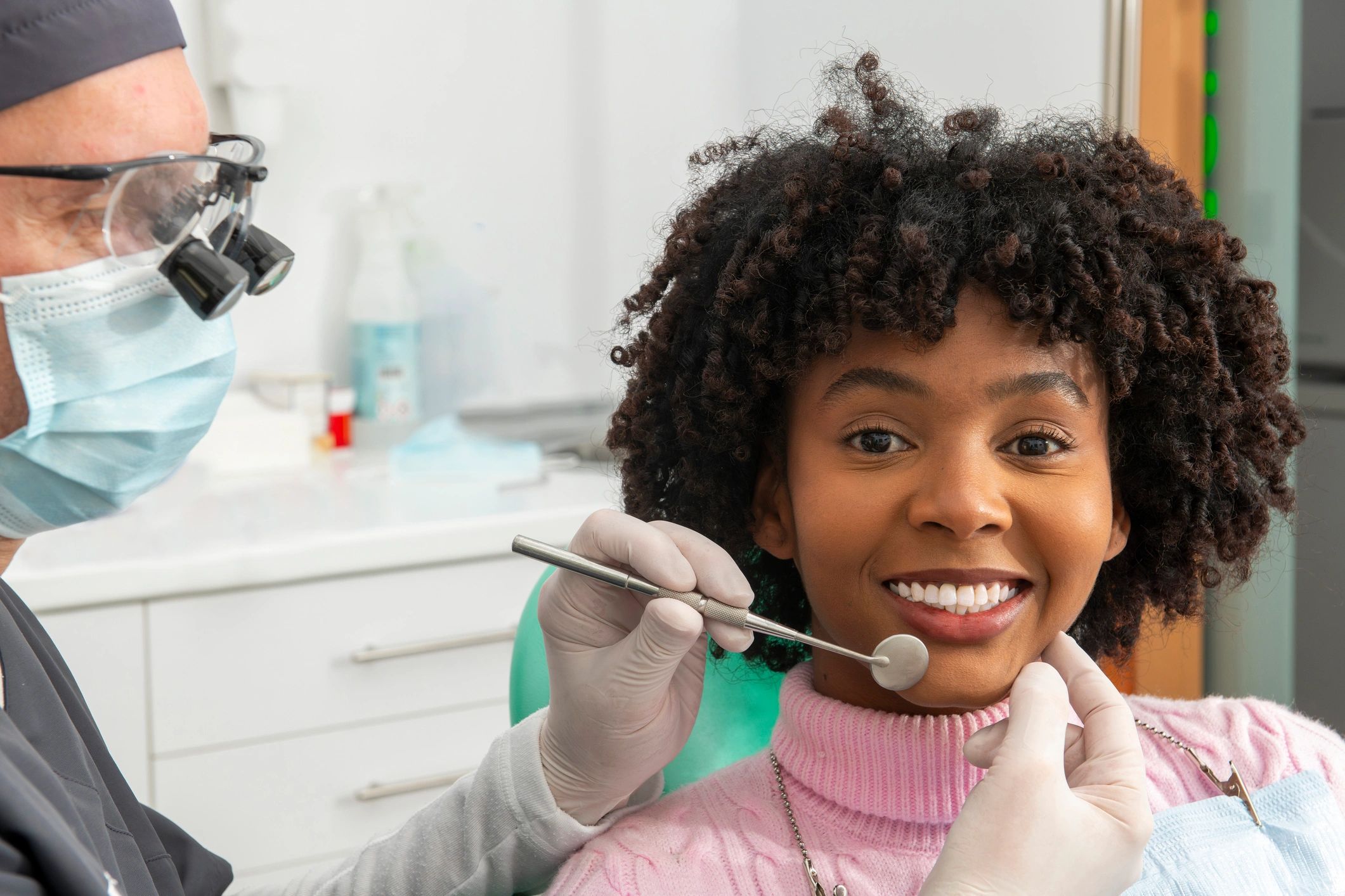 Dentist examining a smiling patient's teeth in clinic