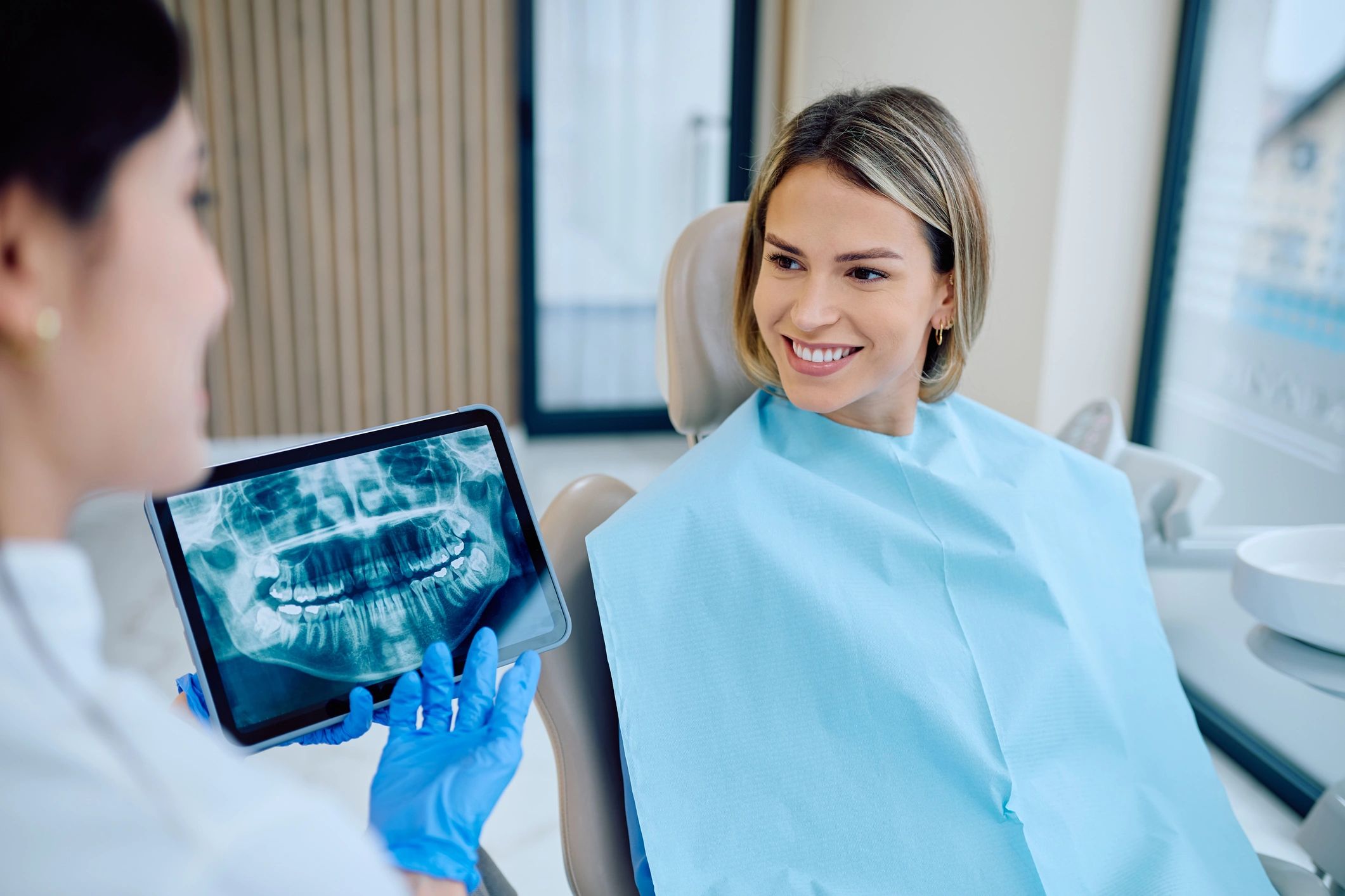 Dentist explaining treatment options to a smiling patient in a modern clinic
